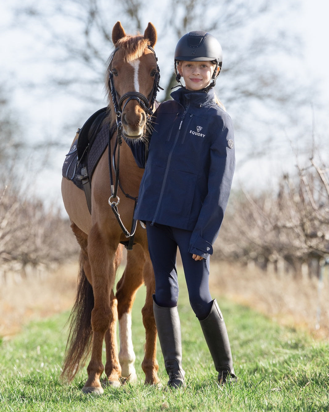 Girl with horse wearing EQUIDRY waterproof jacket. Equiflair riding apparel. Navy equestrian jacket.