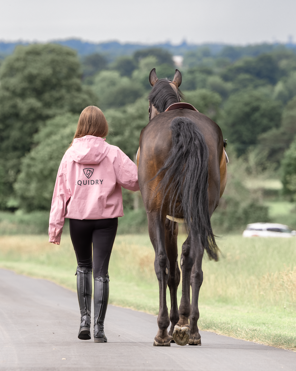 Woman walking horse wearing pink EQUIDRY equestrian waterproof jacket. Horse riding apparel. Equiflair.