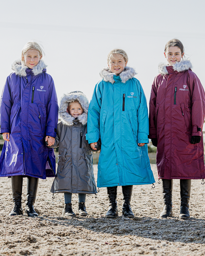 EQUIDRY Evolution Lux children's Warm Waterproof Winter Horse Riding Coat Thick Fleece Lining with Faux Fur Trim Hood being shown in purple, turquoise, plum/ charcoal/grey 