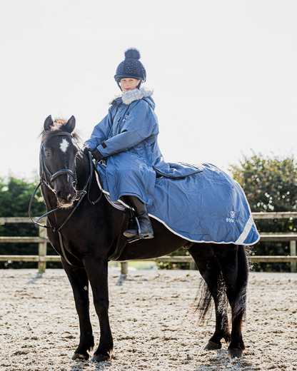 EQUIDRY Evolution Lux children's Warm Waterproof Winter Horse Riding Coat Thick Fleece Lining with Faux Fur Trim Hood being shown in steel blue on horse 