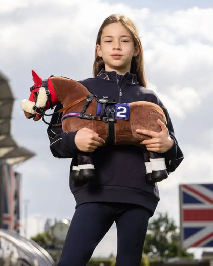 Lemieux Toy Pony Chancer at Equiflair: Girl with plush thoroughbred horse toy ready for horse riding lesson with British flag backdrop.