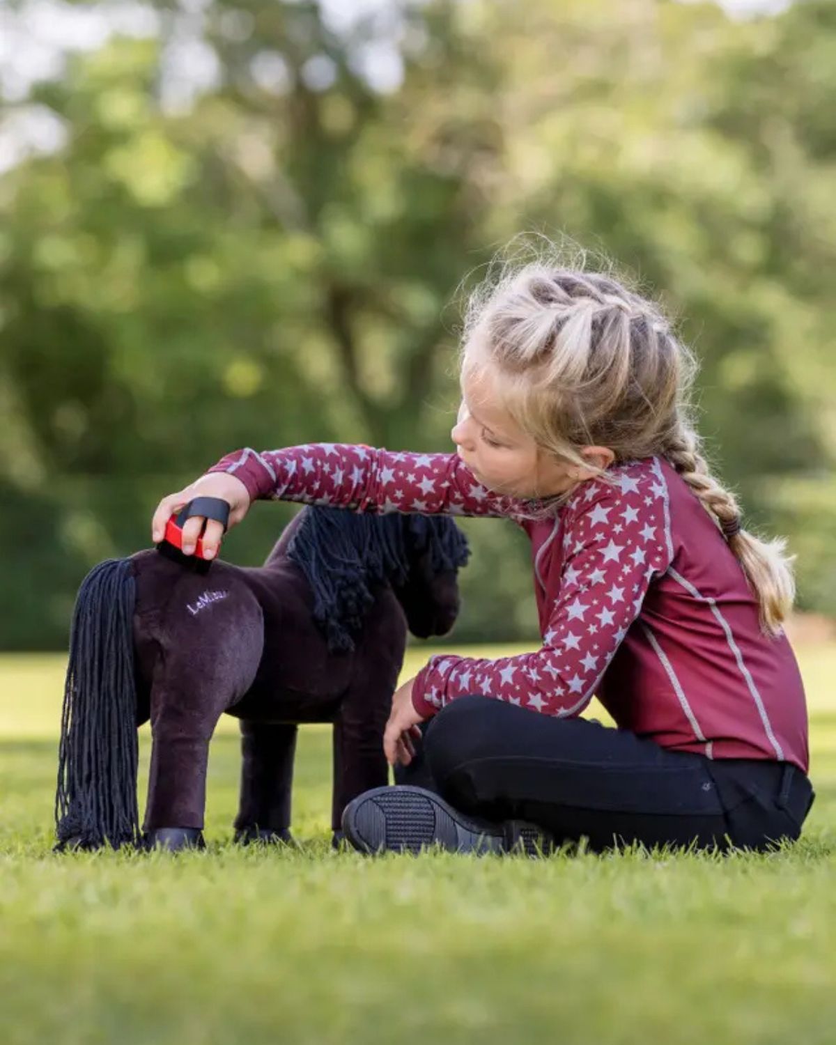 Child brushing Lemieux Toy Pony Freya.  Horse toy on grass. Equiflair