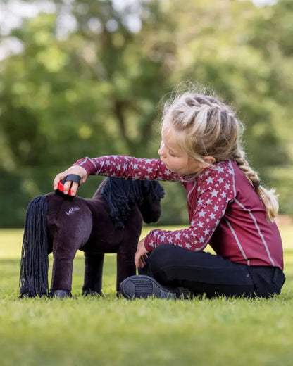 Child brushing Lemieux Toy Pony Freya.  Horse toy on grass. Equiflair