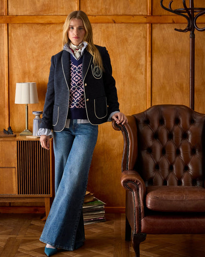 Joules Navy Blazer with Shawl Collar - Woman in herringbone jacket with piped trim and jeans leaning against leather chair.