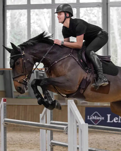 Equestrian Jumping: Horse and Rider Leaping Over Jump with LeMieux Branding Visible. Equestrian Sport.