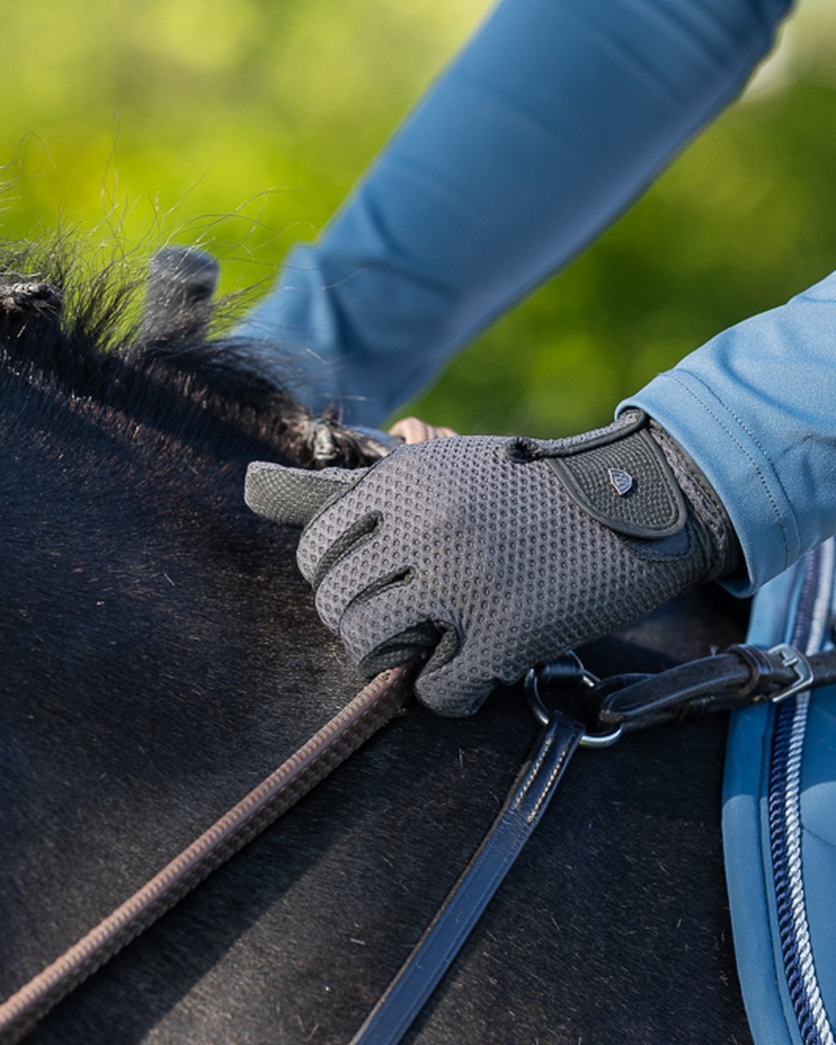 Woof Wear Event Glove Black: Equestrian riding gloves for superior grip & performance. Close up of a rider's hand holding reins.