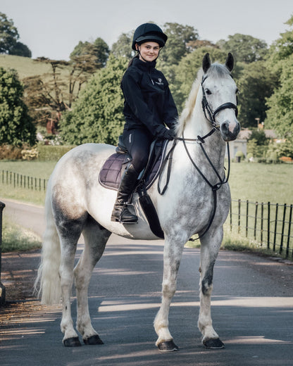 Young equestrian rider on gray horse wearing Equidry riding leggings by Equiflair, equestrian apparel, outdoor riding