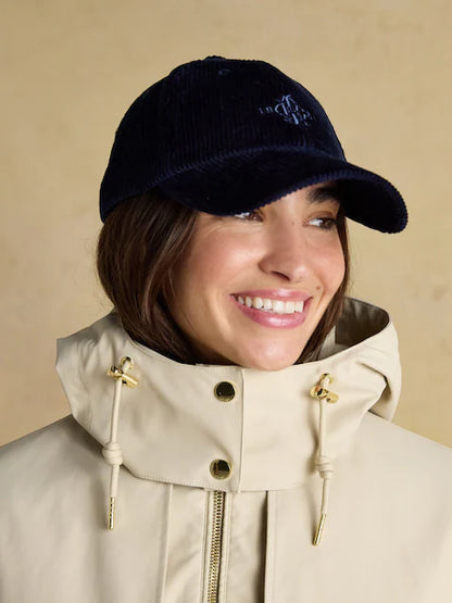 Woman in Joules Waterproof Coat with Hood and Corduroy Cap. Recycled Polyester Rain Jacket.
