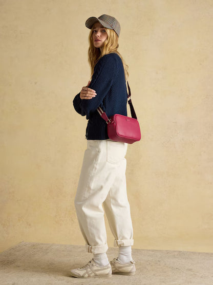Joules Trent Berry Red Crossbody Bag: Stylish red bag worn by a woman in casual attire. Equiflair store.