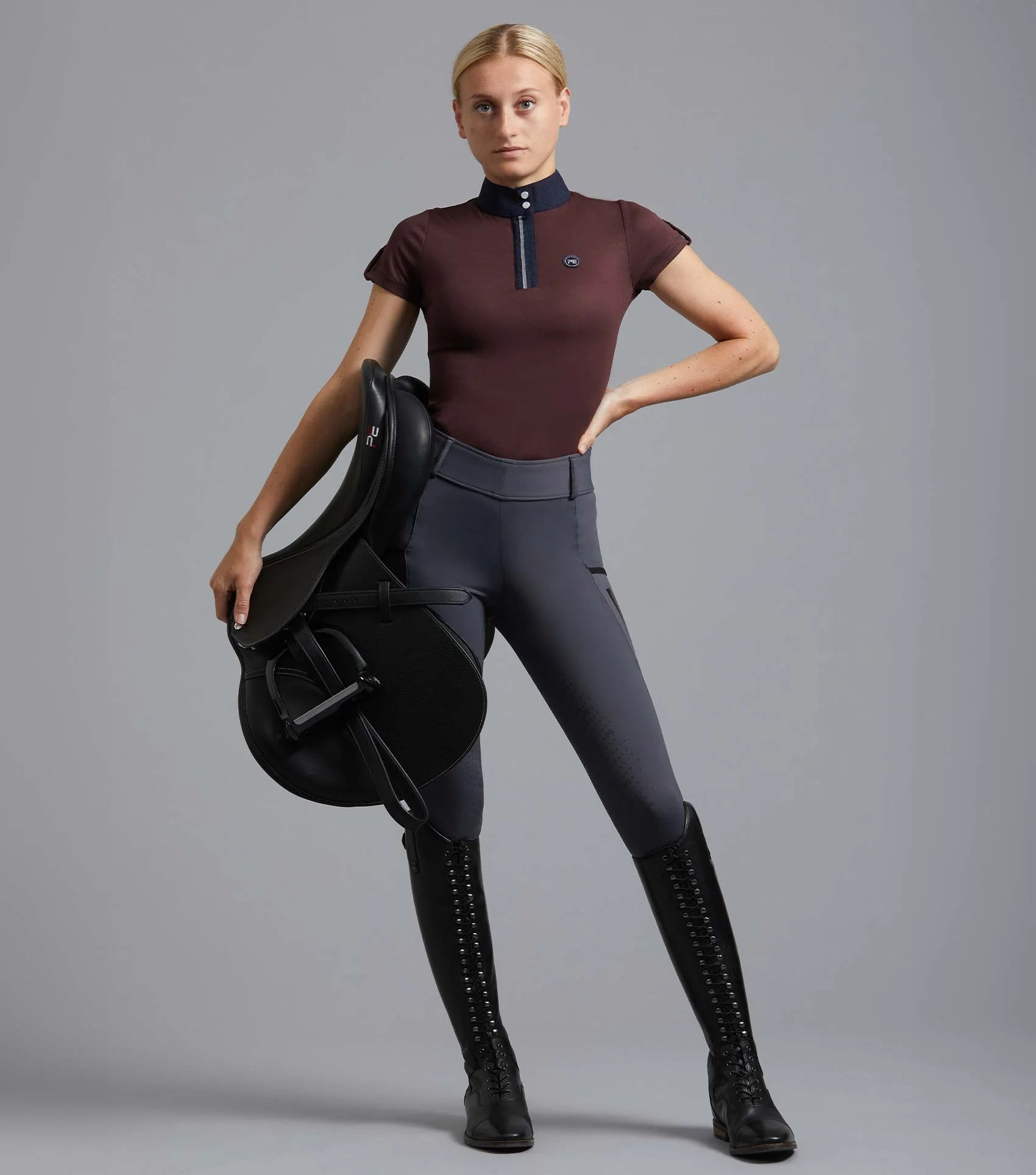 Premier Equine Wine Riding Top: Equestrian Woman with Saddle. Stylish women's horse riding apparel.