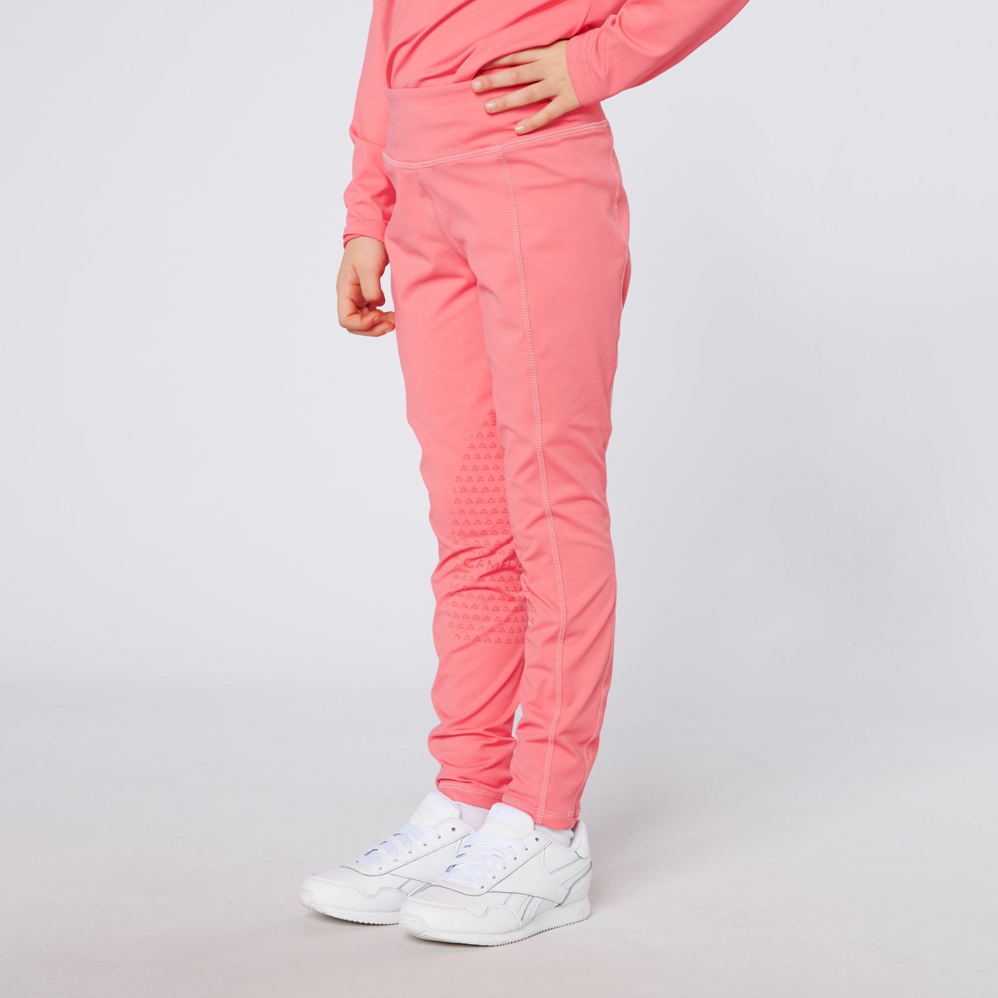 Junior pink baselayer bottoms with geometric grip pattern & white Reebok sneakers. Equestrian kids fashion by Equiflair.