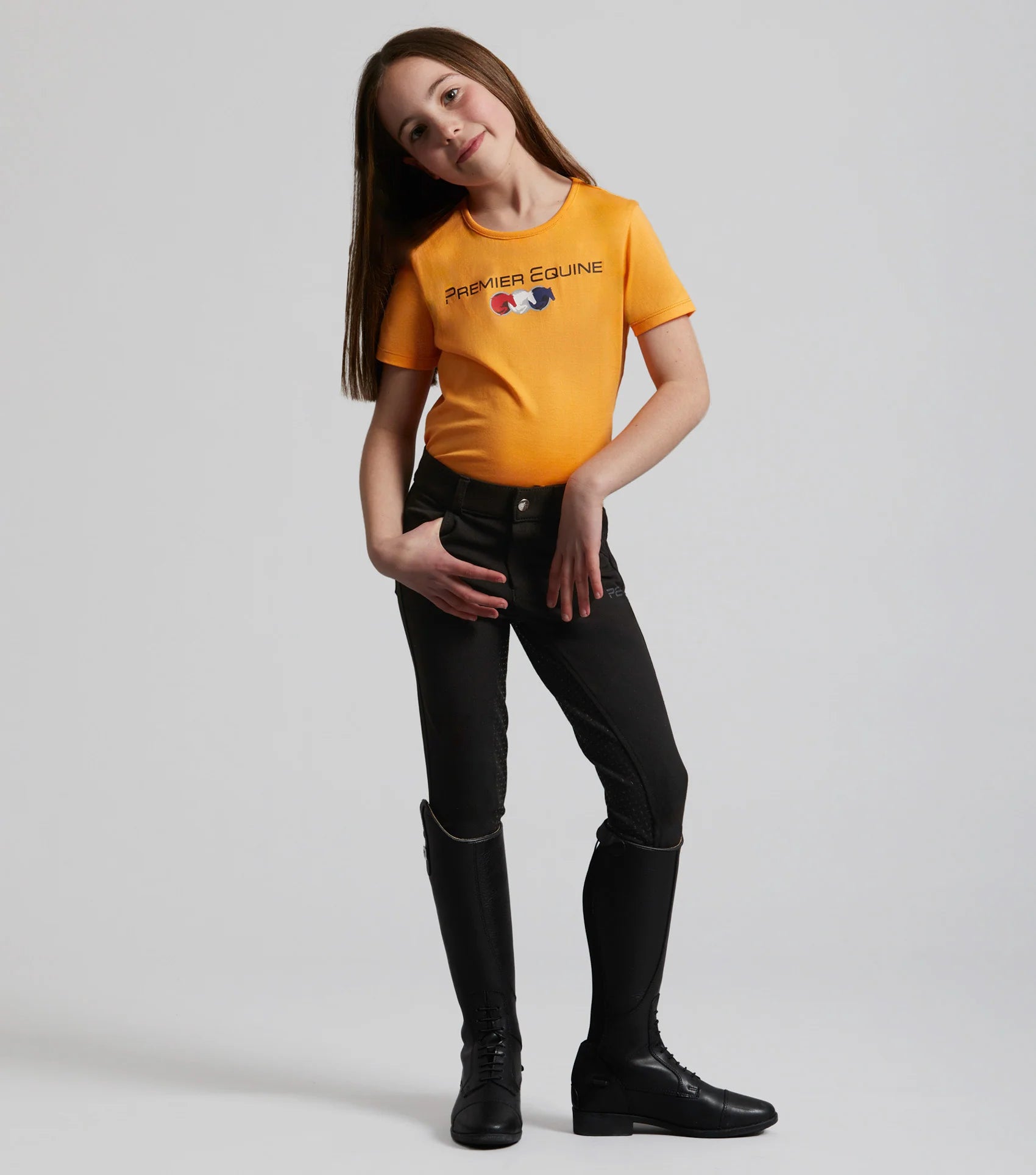 Girl wearing Premier Equine Chiaro Orange Cotton Riding T-Shirt. Equestrian apparel for girls.