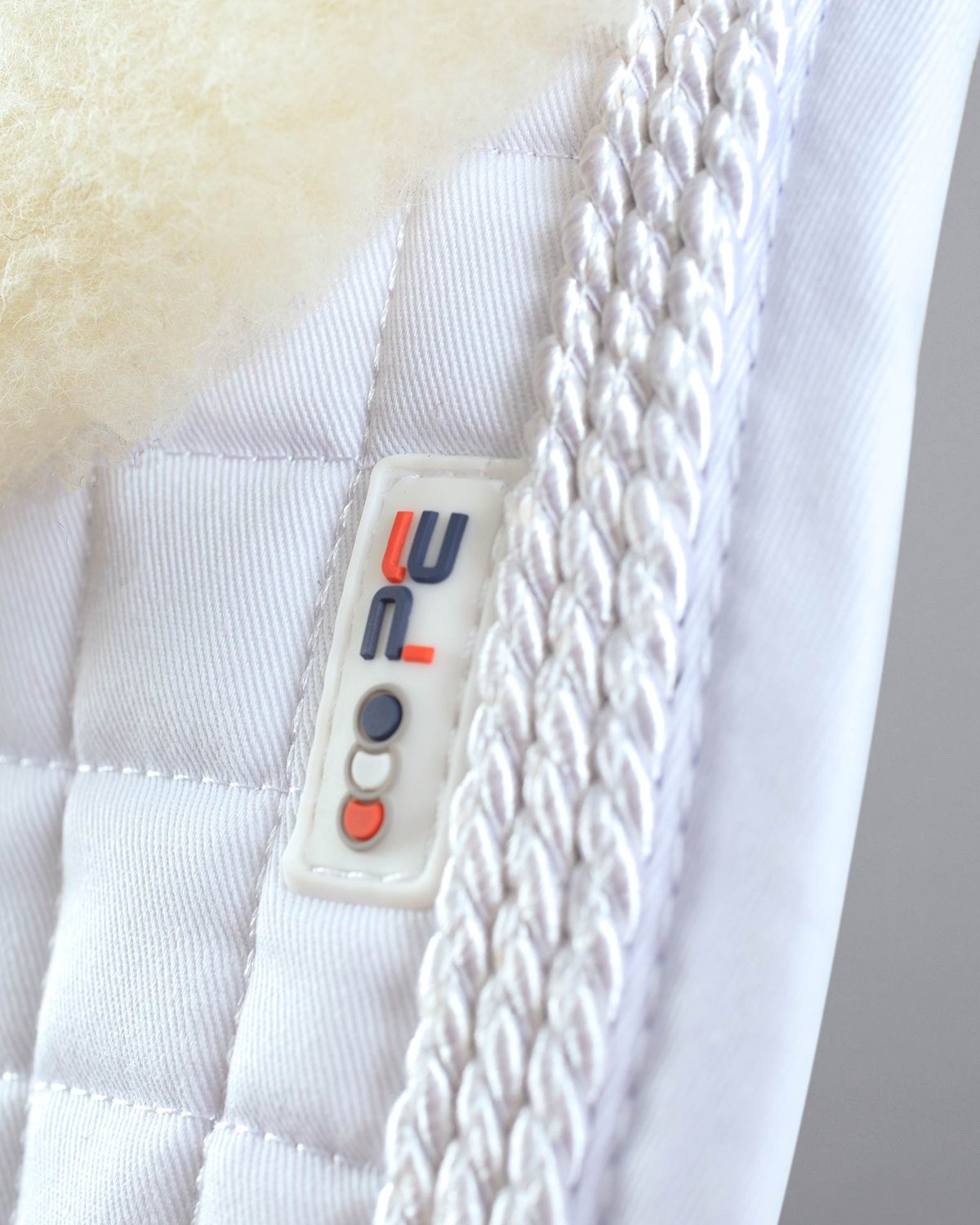 PREMIER EQUINE pony dressage saddle pad, white merino wool lined, close-up. Equestrian equipment from Equiflair.