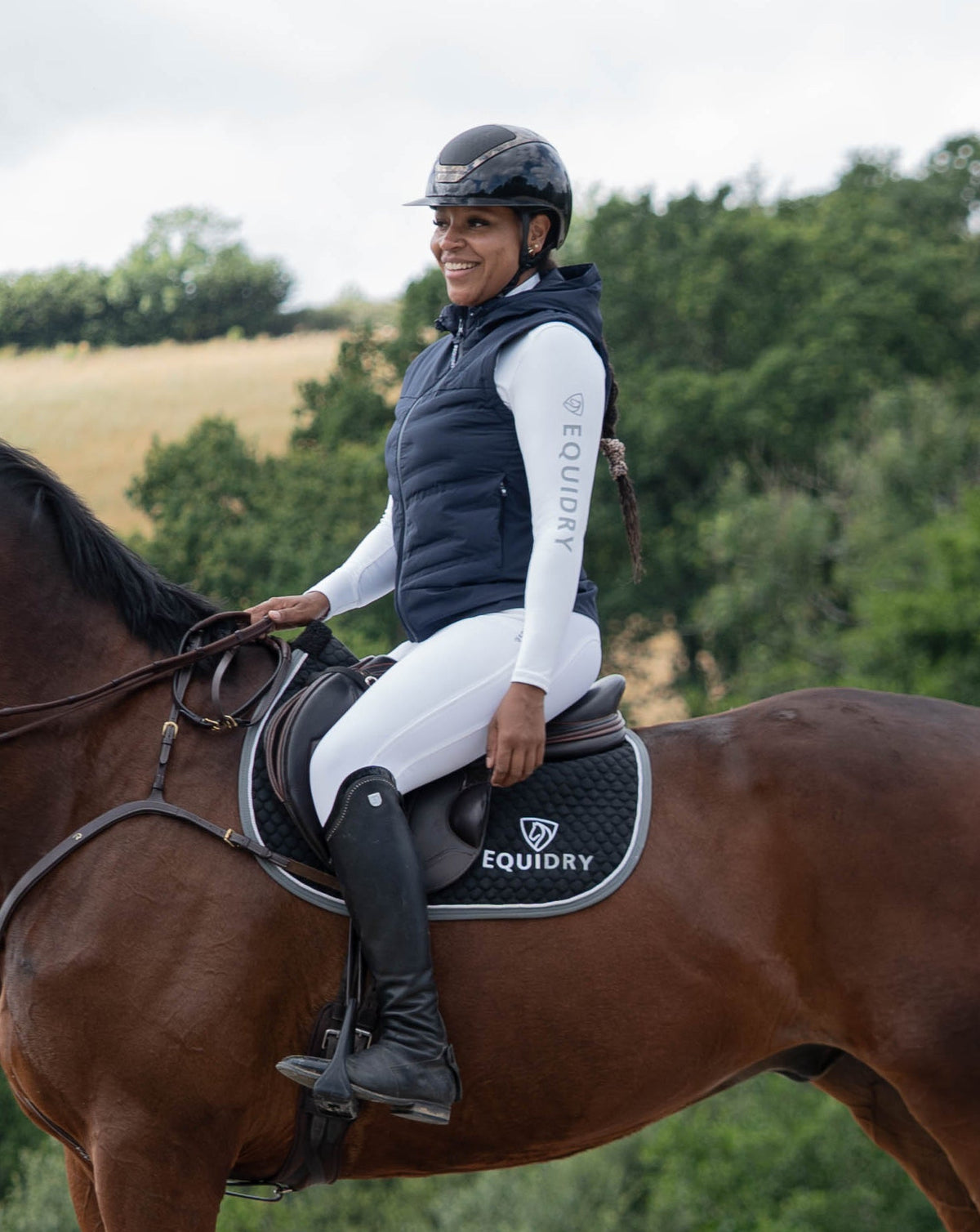 Woman in EQUIDRY navy lightweight gilet and riding gear on a horse