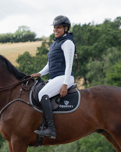Woman in EQUIDRY navy lightweight gilet and riding gear on a horse