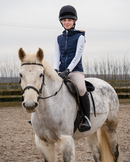 Child rider in navy Equidry gilet on a grey horse, perfect for horse riding.