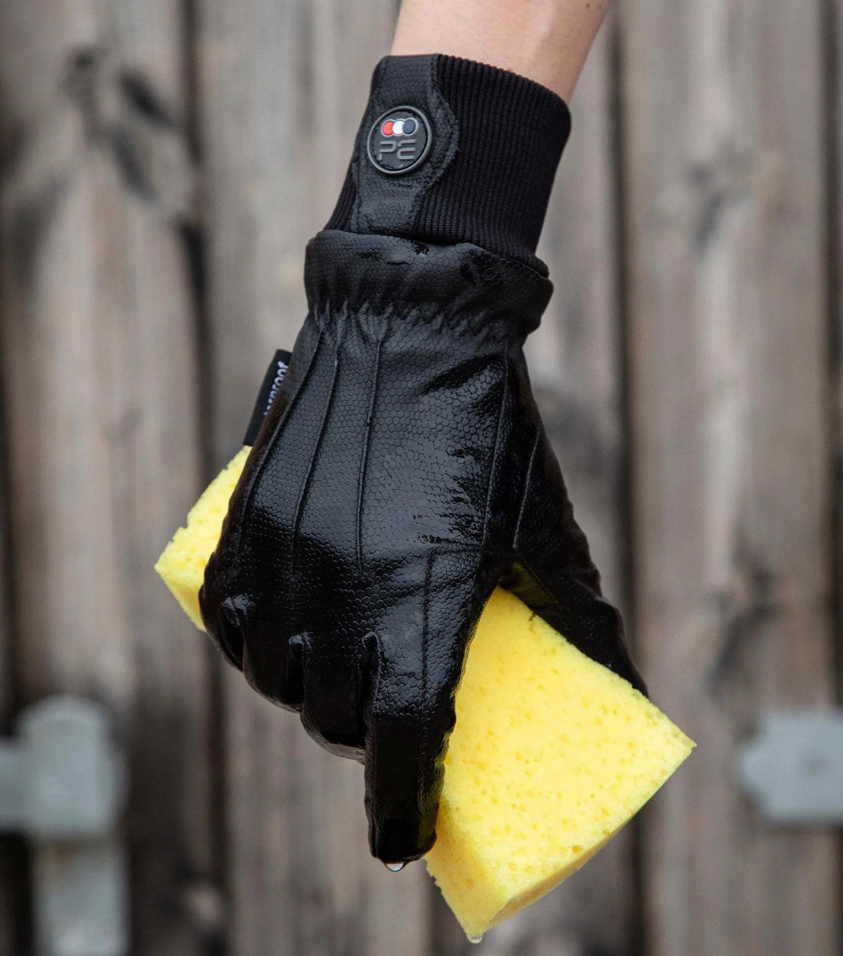 Waterproof Riding Gloves by Premier Equine, Black Gloves Holding Sponge, Equestrian Gloves