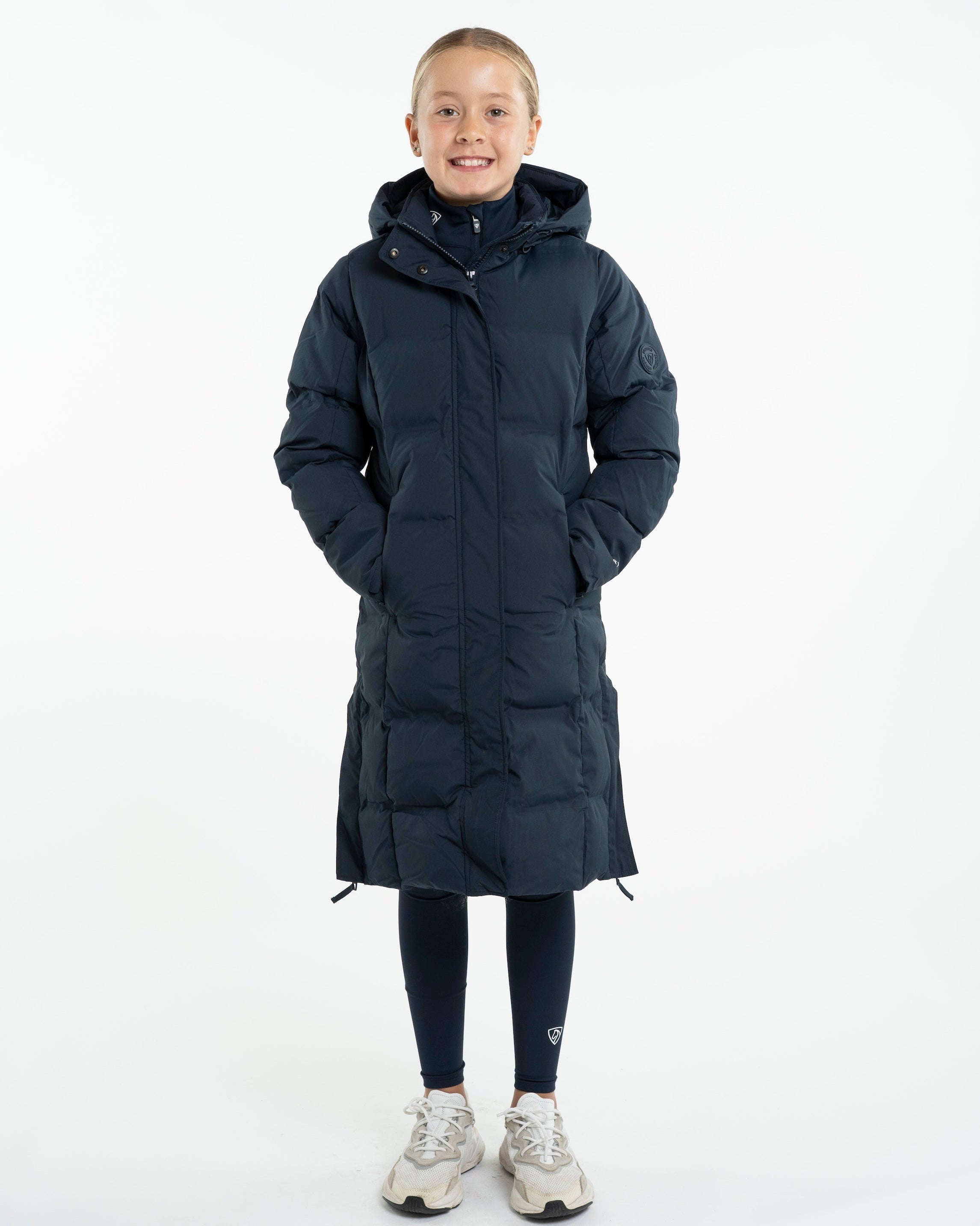 Girl in EQUIDRY THORA Waterproof Riding Puffer - Navy. Stylish equestrian girl's riding coat.
