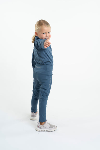 Equidry: Young girl in steel blue riding leggings giving a thumbs-up. Water-repellent knee grip leggings for kids.