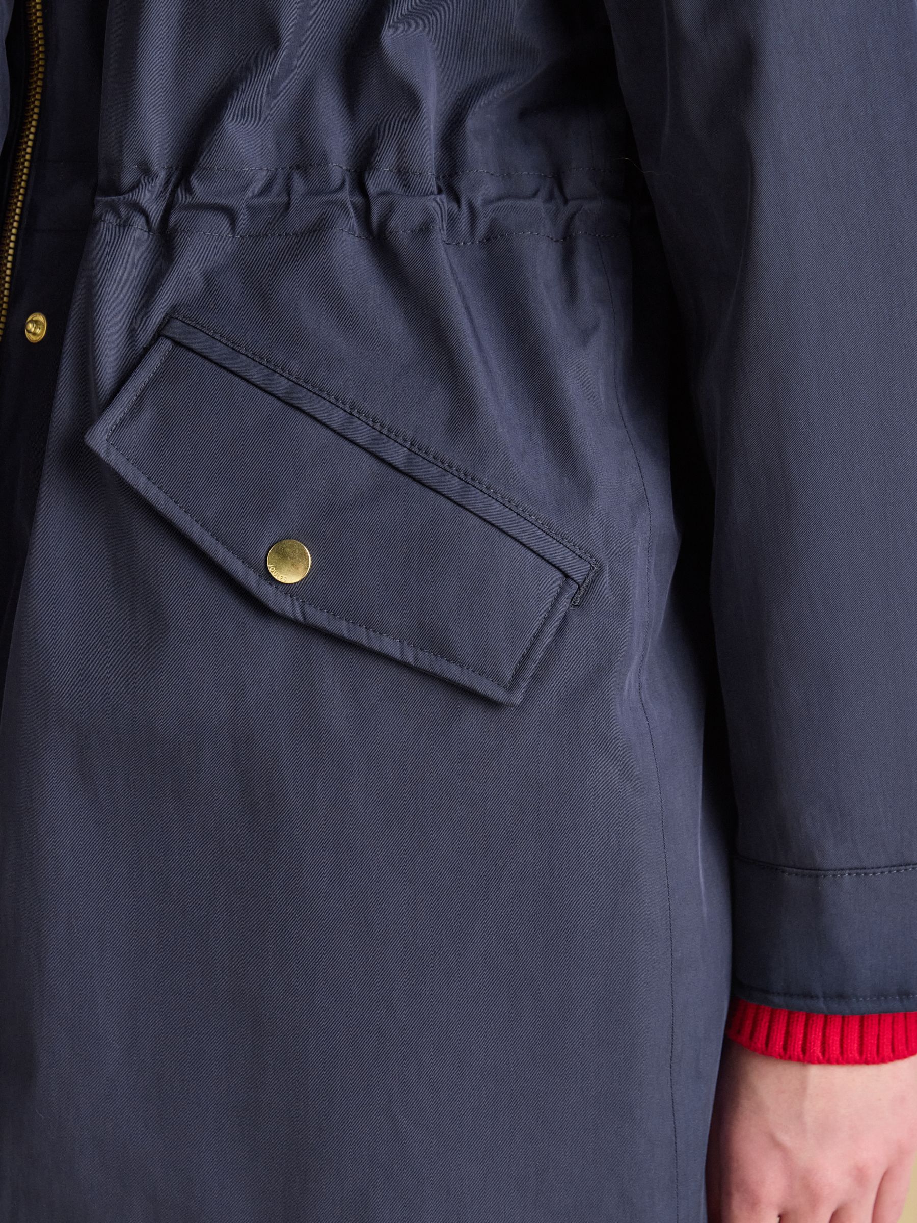 Navy Joules raincoat pocket with gold button detail and red trim peeking out.