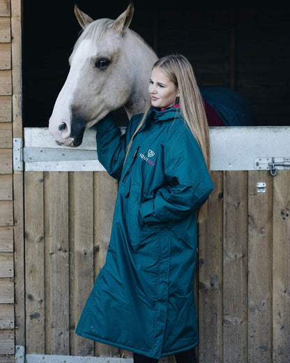 Equiflair: Woman in EQUIDRY waterproof riding coat with horse in stable. Equestrian apparel.