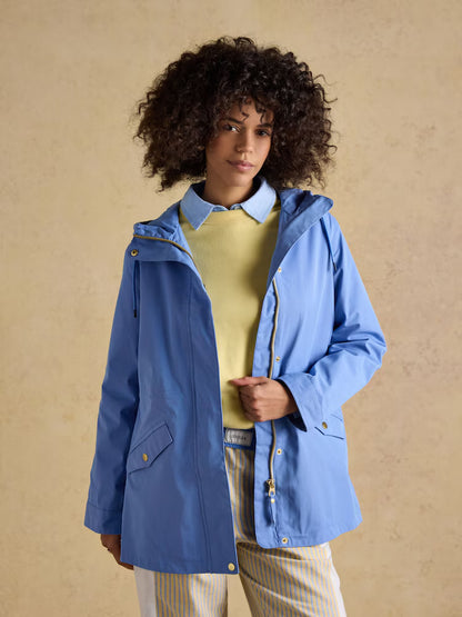 Woman wearing a Joules blue hooded waterproof raincoat, perfect for rainy days.