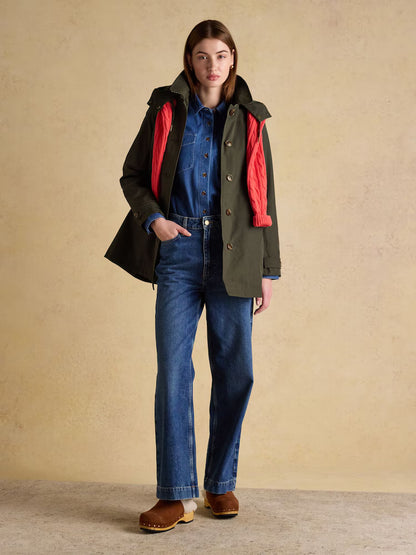 Woman in Joules Khaki Green Waterproof Raincoat with Hood and Red Scarf. Stylish Women's Outerwear.