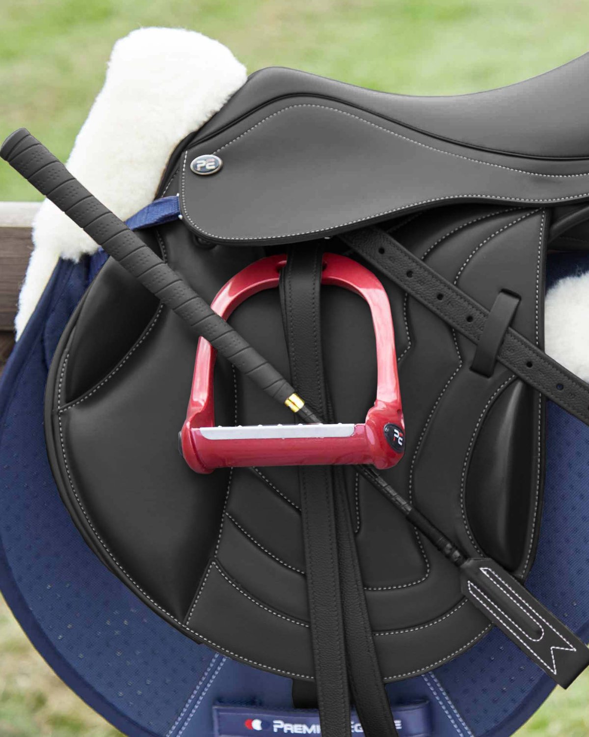 Black leather horse saddle with red stirrups and whip from Equiflair, equestrian riding equipment, dressage saddle