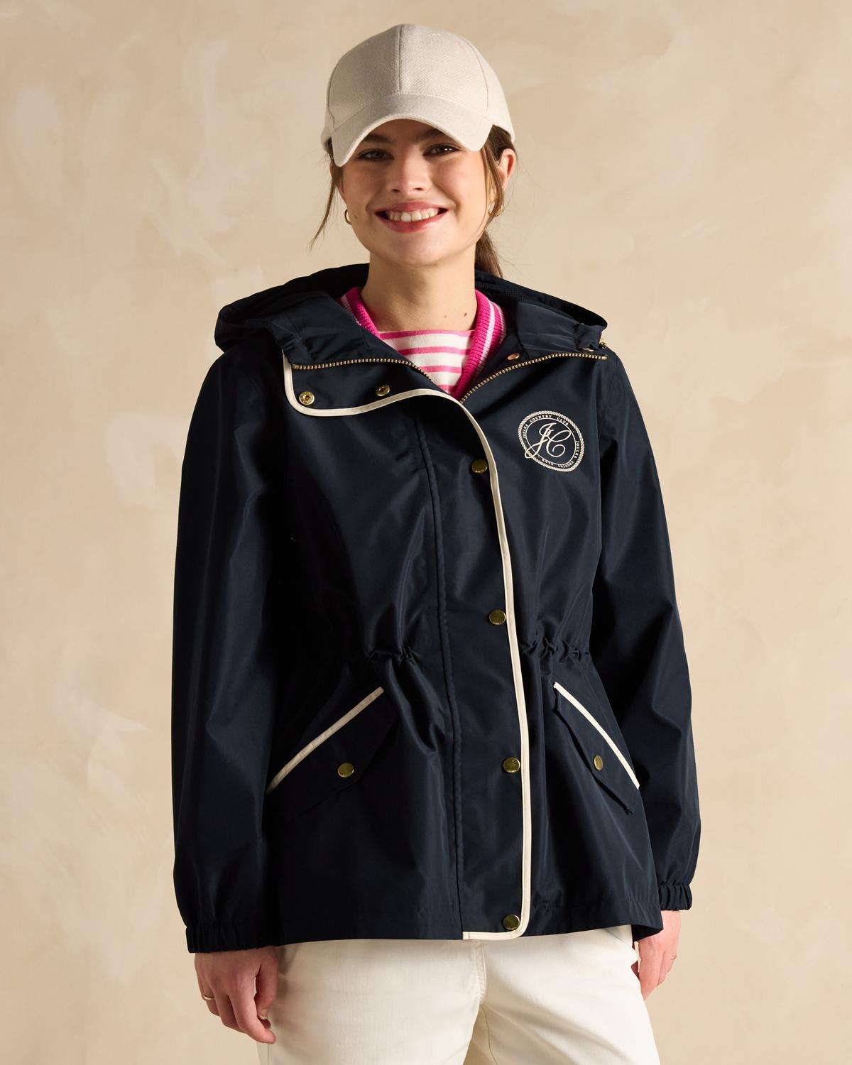 Joules Holt Navy Packable Raincoat with Hood. Woman wearing Joules outerwear. Waterproof jacket with logo.
