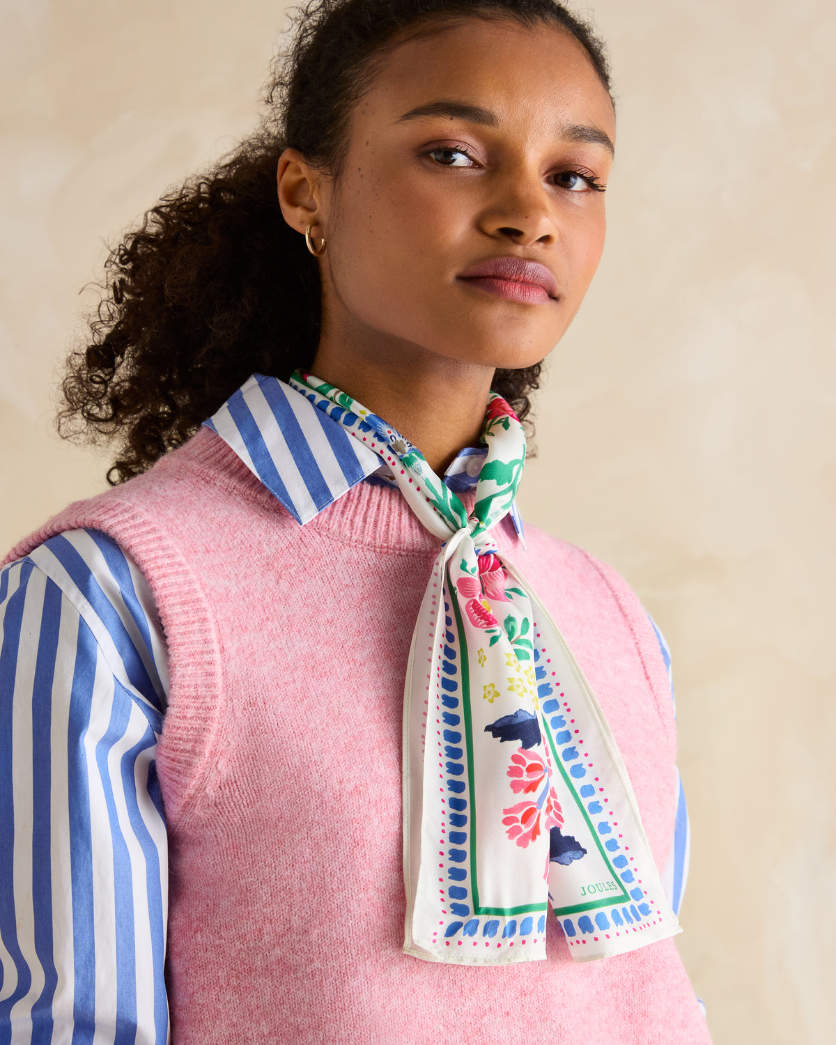 Joules Skinny Scarf: Woman wearing floral silk scarf, pink sweater vest & striped shirt. Equiflair fashion.