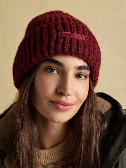 Red Joules Rosa Beanie knit hat, woman wearing winter fashion beanie with Joules logo.