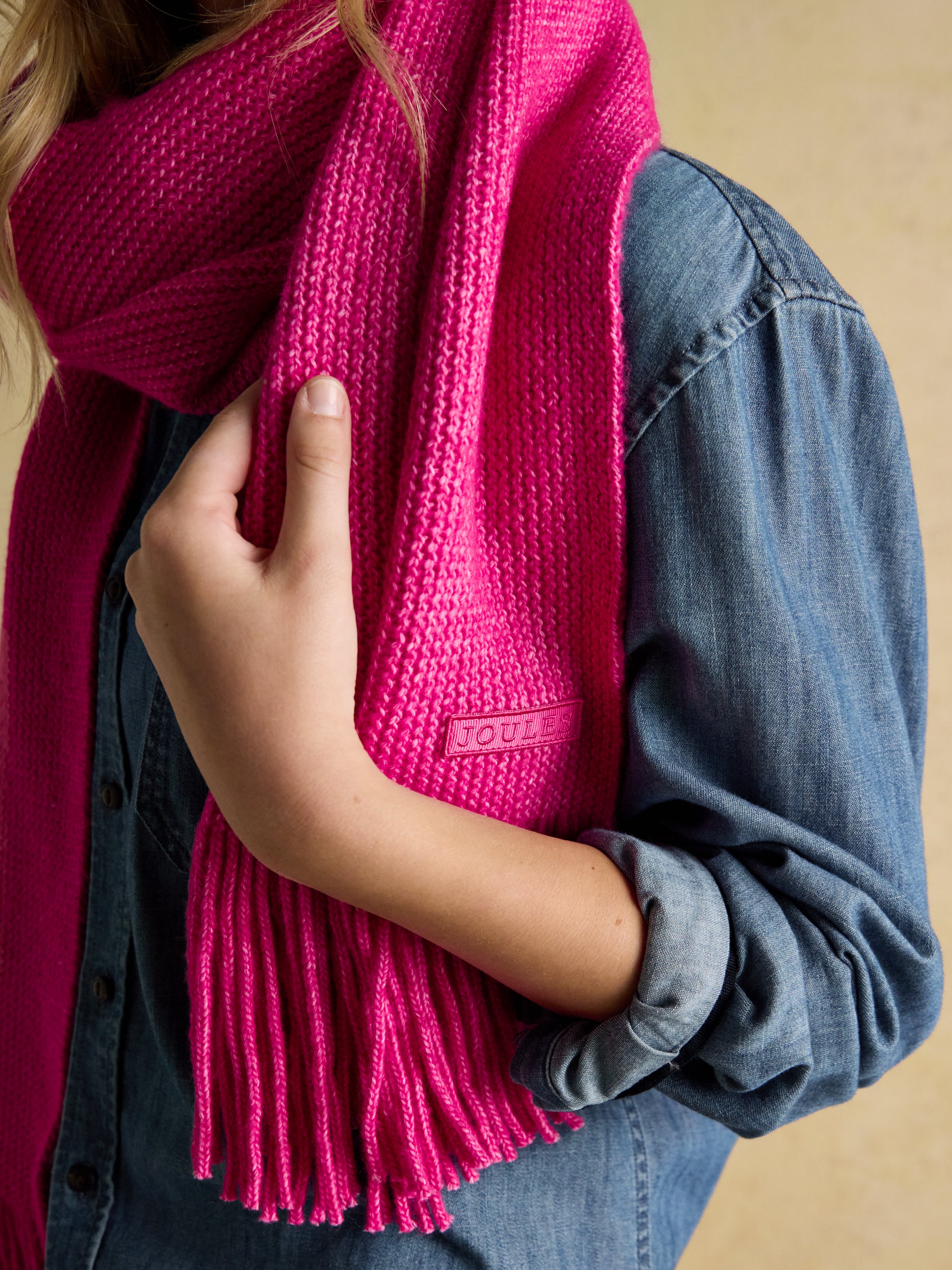 Joules Rosa Pink Scarf: Soft Knitted Scarf with Fringed Edges. Model wearing Joules scarf.