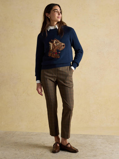 Woman in dog sweater, white shirt, plaid pants, and brown loafers. Joules Intarsia Monty Dog Cotton Blend Jumper.