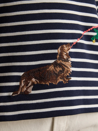 JOULES Festive Dog Breton Top: Navy striped boat neck with a dog embroidery near a christmas tree.