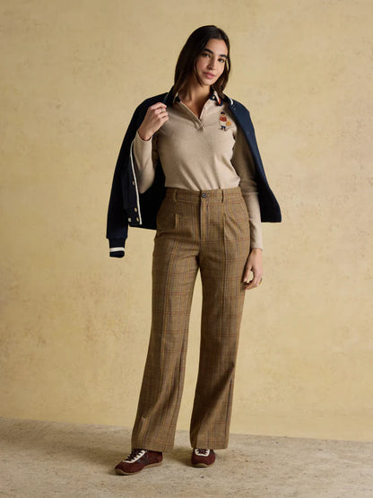JOULES FAIRFIELD JONTY NEUTRAL Polo Shirt: Woman in beige long-sleeve polo with embroidered detail and jacket, brown plaid pants.