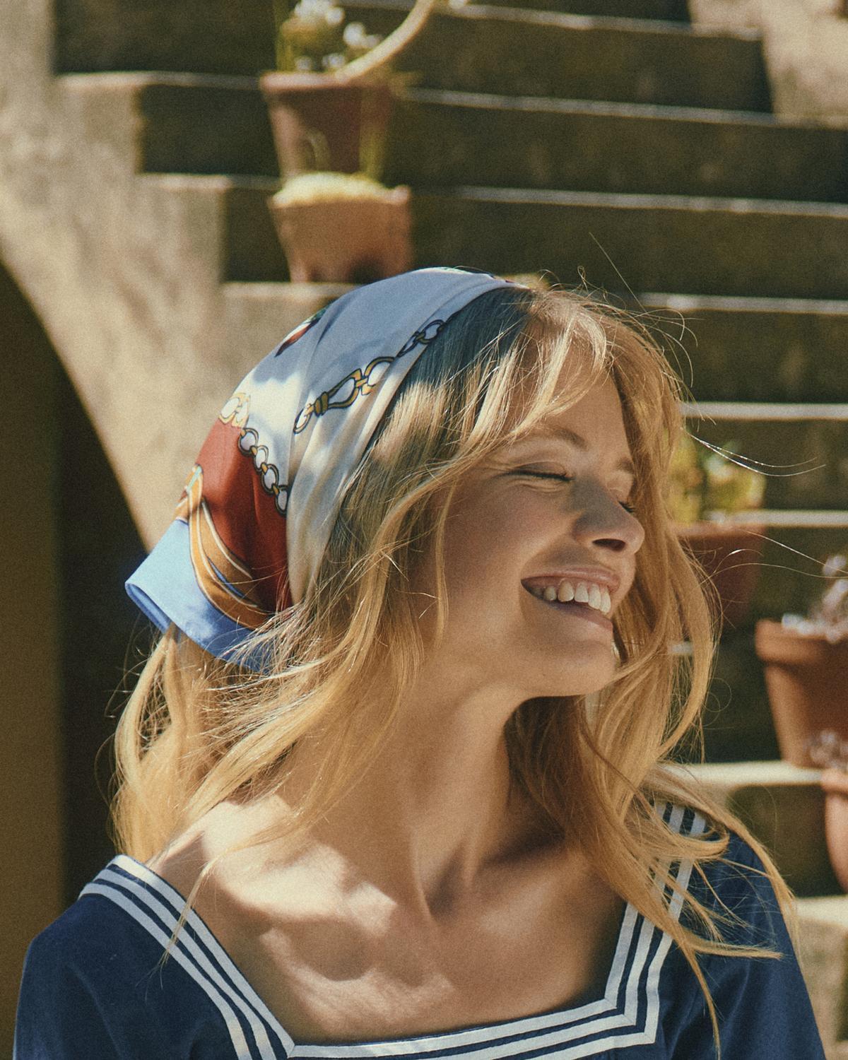 Smiling woman with Joules headscarf, styled blue nautical square scarf from Equiflair. Happiness and style.