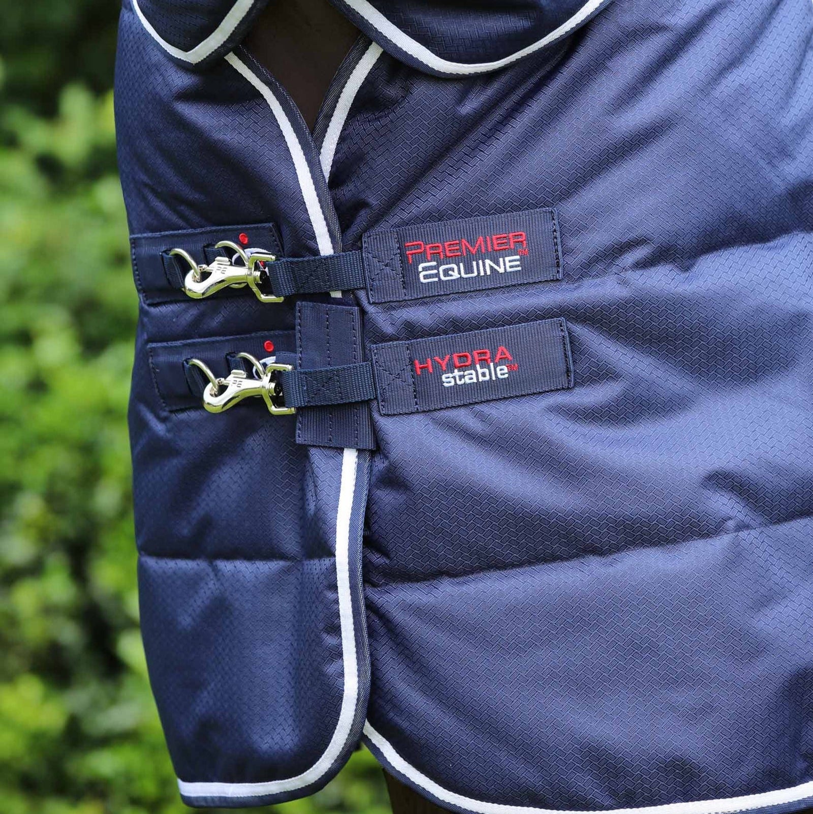 Premier Equine Hydra 200g Stable Rug with Neck Cover: Close-up of buckles and branding on a blue horse blanket.