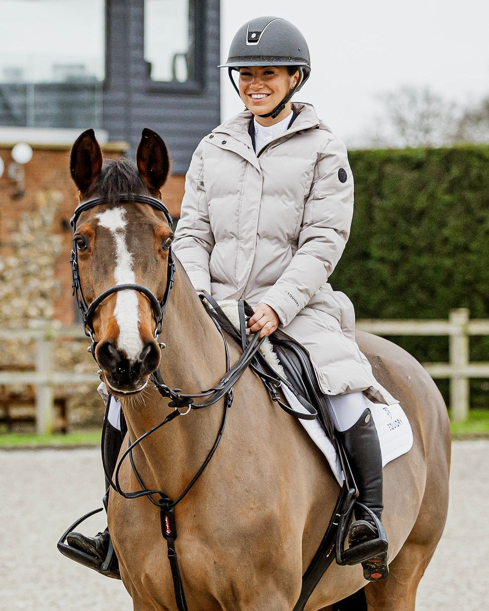 Equestrian Style: Woman Riding Horse in EQUIDRY Thora Waterproof Puffer Jacket from EquiFlair. Stay Warm & Dry!