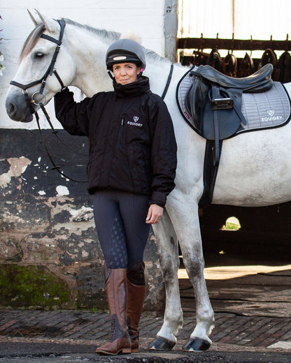 EQUIDRY women's waterproof short blouson style horse riding jacket in rich brown stood with horse