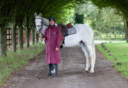 Man with white horse wearing Equidry Evolution plum coat on tree lined path. Equestrian riding gear from Equiflair.