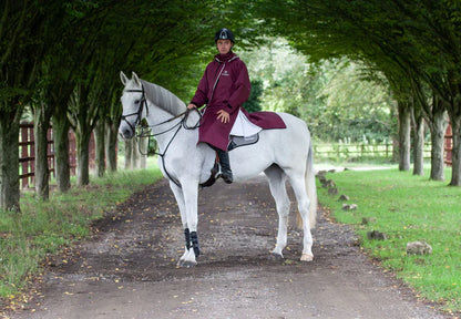 Equestrian rider on a white horse wearing EQUIDRY coat reflective Plum - waterproof riding gear.