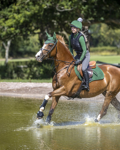 Equestrian horse and rider in green, eventing in water, wearing LeMieux Hunter Green Suede Close Contact Square pad