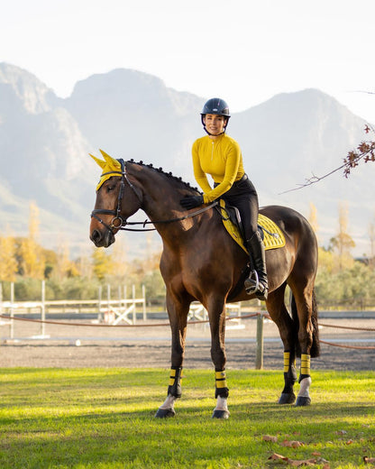 Woman riding horse wearing LeMieux Loire Dijon saddle pad from Equiflair. Equestrian style, horseback riding gear.