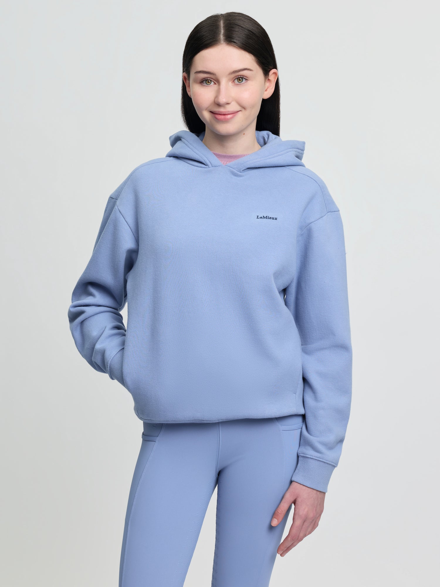 LeMieux Young Rider Sia Hoodie Powder Blue: Girl wearing oversized blue hoodie with LeMieux logo and matching leggings. Equiflair