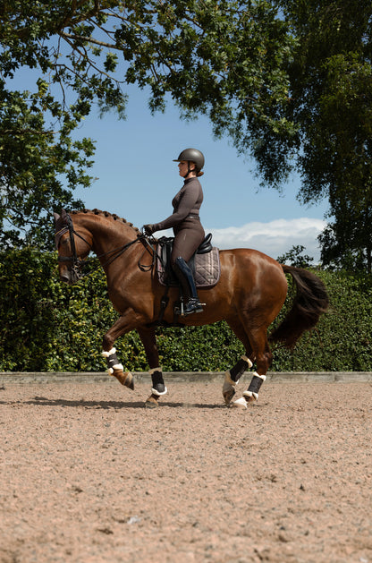 Equestrian dressage rider on brown horse with LeMieux Heritage Check Dressage Square Cocoa saddle pad