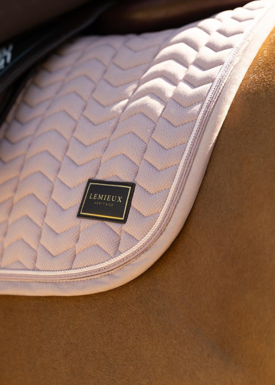 LeMieux Heritage herringbone jump saddle pad in wild rose pink, showing detailed quilting and branding on a horse.
