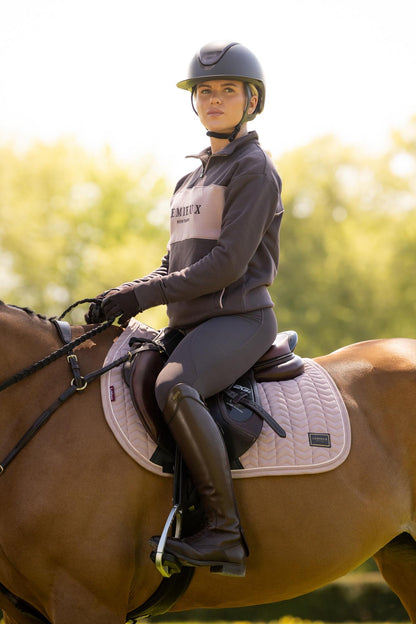 Equestrian rider on a horse wearing LeMieux Heritage saddle pad in Wild Rose, showing saddle and attire.