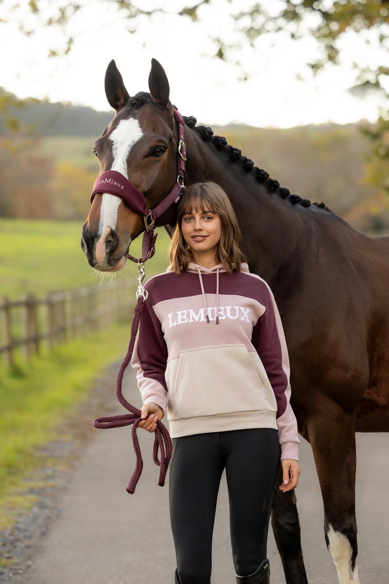 Woman in LeMieux Wild Rose colour block hoodie with a horse. Equestrian fashion.