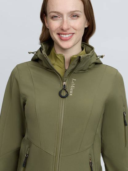 Woman in LEMIEUX CELINE SOFTSHELL JACKET in Willow Green, featuring a hood and zipper.