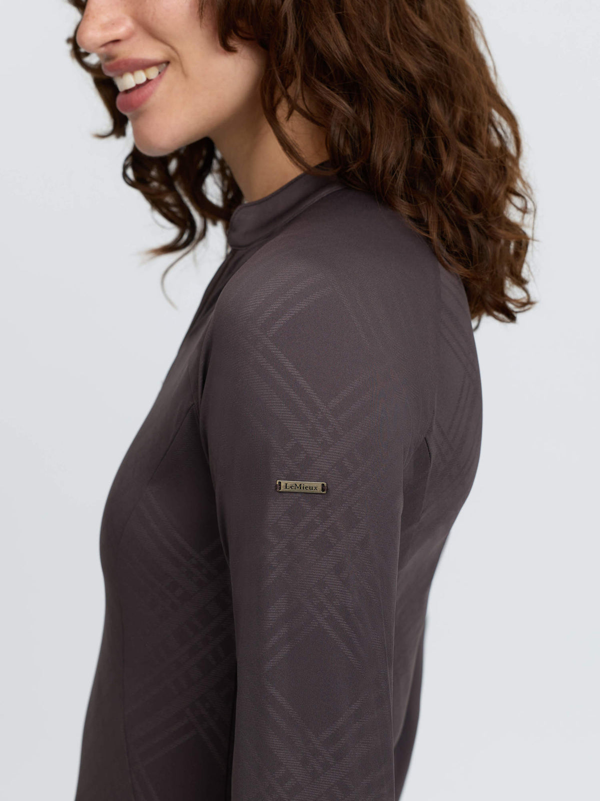 LeMieux Heritage Check Long Sleeve Base Layer in Cocoa - Woman wearing equestrian top with logo.
